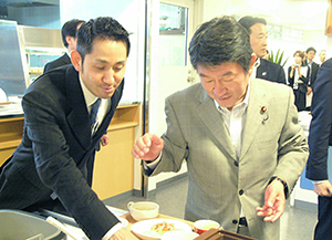 食堂で自分でご飯をよそう茂木敏充経産大臣（右）と谷田千里タニタ社長