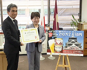 兼松康熊本支社長（左）が宮尾千加子熊本県教育長に目録を贈呈した