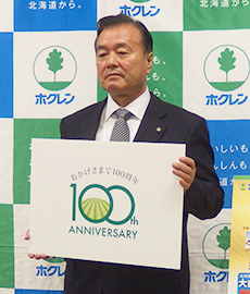 100周年記念ロゴマークを抱えPRする内田和幸会長