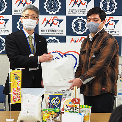 原和彦理事長（左）から留学生へ生活支援品を贈呈