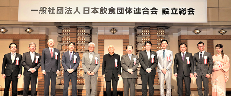 壇上に並ぶ服部幸應会長（左から6人目）、佐藤裕久副会長（同5人目）ら食団連役員
