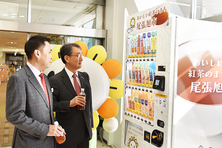 自動販売機を利用する柴田浩市長（右）（左は小林雅敬キリンビバレッジ執行役員中部圏統括本部長）