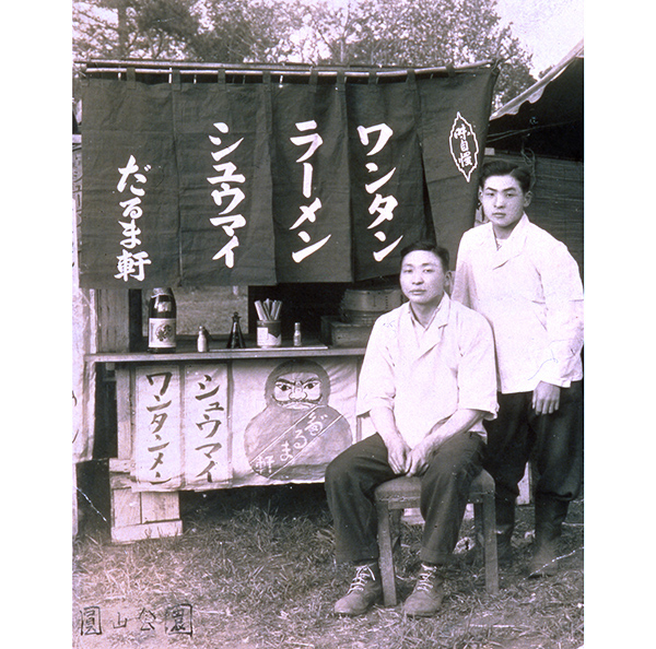 「だるま軒」の屋台前に立つ西山仙治氏（左）と西山製麺創業者の西山孝之氏（昭和25年ごろの札幌円山公園花見会場）