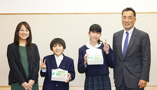 贈呈式で左からロッテの木下温美氏、翔英小学校の児童、羽村章特任教授