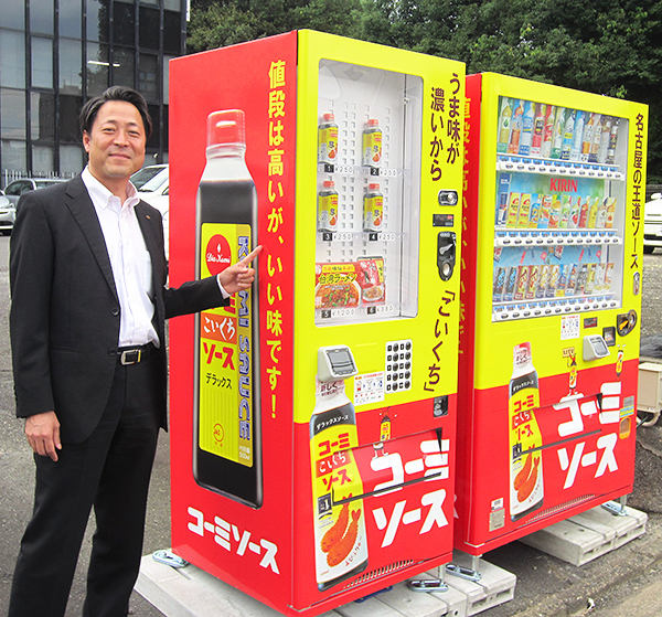 ラッピング自販機の出来栄えに笑顔を見せる川澄亮太社長