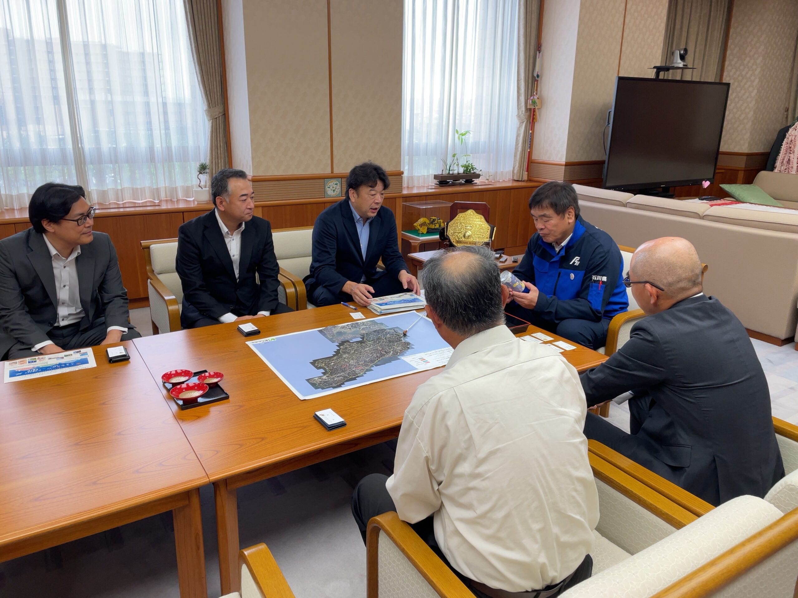 左から時計回り、三菱食品の末永光史マネージャー、大曽根謙支店長、森川博昭本部長、馳浩石川県知事、昭文社の丸岡康太部長、加賀しずく研究会の下田覚会長