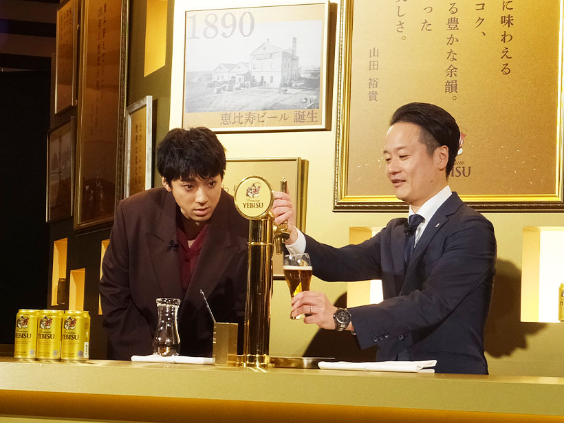荒木ブランドマネージャー(右)のビール注ぎをじっくり観察する山田裕貴